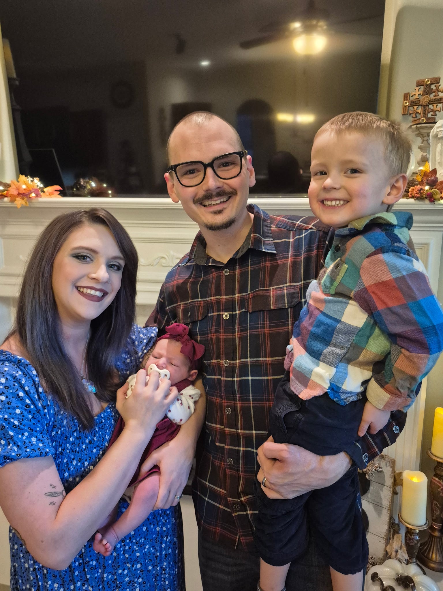 Family of four with a baby and a young child indoors, likely in a living room.